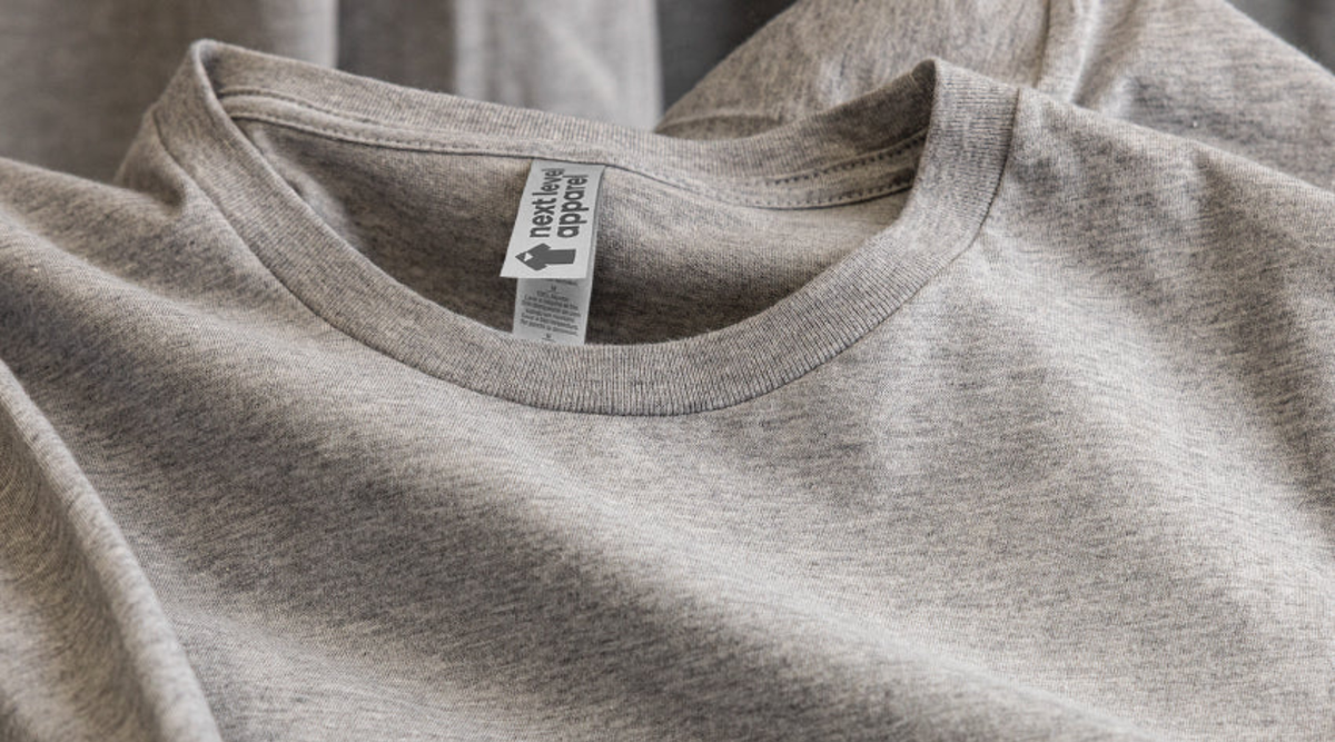 Heather gray Next Level Apparel crew neck t-shirt laid flat, showing the neck label, ribbed collar, and fabric texture